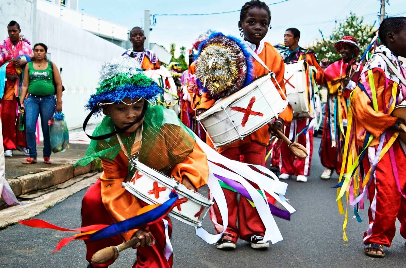Crianças com tambores e trajes coloridos de fitas participando do desfile da Folia de Reis