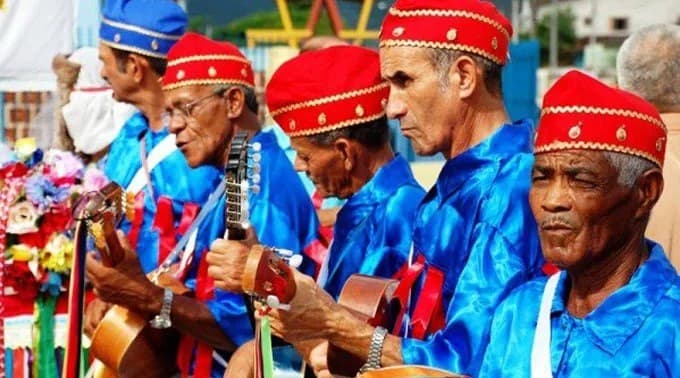 Violeiros da Folia de Reis com boina vermelha e casaco azul, tocando viola e violão